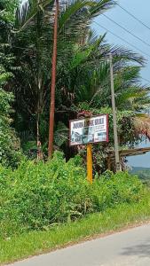 ein Schild an der Seite einer Straße in der Nähe einer Palme in der Unterkunft OYO HOME 90751 Jasura Lodge Kiulu in Tamparuli