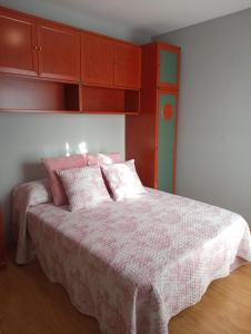 una camera da letto con un letto con una coperta rosa e armadi in legno di EnSAN CIPRIAN URB. RÍO COBO a Cervo