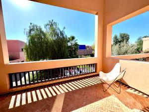 a balcony with a white chair and two large windows at Al Maaden Ryad 69 a Marrakesh in Marrakesh