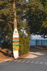 a surfboard leaning against a tree next to the ocean at Nisi Glamping in Paralia Rachon