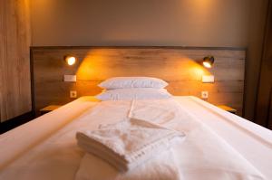 a white bed with two white pillows and a wooden headboard at Hotel Sportforum in Rostock