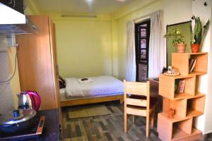 um pequeno quarto com uma cama e uma secretária com uma cadeira em Tanani Newa Home Arnnapurna em Patan