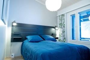 a bedroom with a blue bed with a large headboard at Pyhä Snowflake in Pyhätunturi