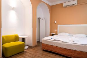 a bedroom with a bed and a yellow chair at Hotel Metro in Budapest