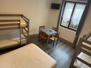 Zimmer mit 2 Etagenbetten sowie einem Tisch und Stühlen in der Unterkunft Hotel Restaurant L'Escale in Sainte-Nathalène