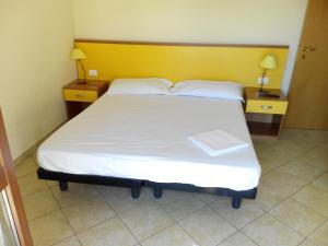 a bedroom with a large white bed with a yellow headboard at Ada Home in Sanremo