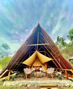 a large thatched tent with chairs in front of it at Tangkahan Eco Glamping 