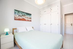 ein weißes Schlafzimmer mit einem Bett und einem Gemälde an der Wand in der Unterkunft Hoso Apartments T1 in Costa da Caparica