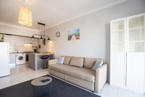 ein Wohnzimmer mit einem Sofa und einer Küche in der Unterkunft Hoso Apartments T1 in Costa da Caparica