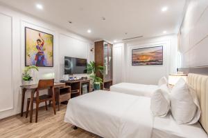 een slaapkamer met een wit bed, een bureau en een tafel bij Reyna Luxury Hotel in Hanoi