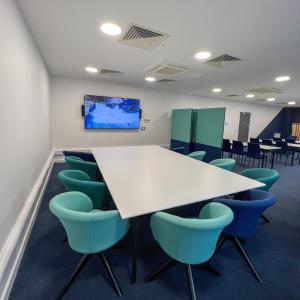 a conference room with a white table and blue chairs at The Base Camp Hotel, Nevis Range in Fort William