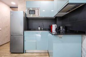 cocina con armarios azules y nevera de acero inoxidable en Apartments Lilia Reus, en Reus