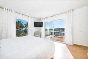 ein weißes Schlafzimmer mit einem Bett und einem großen Fenster in der Unterkunft Luxury Villa with panoramic sea views in Sol de Mallorca