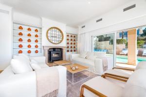 a living room with white furniture and a fireplace at Luxury Villa with panoramic sea views in Sol de Mallorca