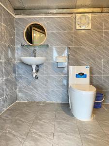 een badkamer met een wastafel, een toilet en een spiegel bij May Home Tà Xùa in Bắc Yên