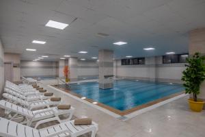 einen Pool mit weißen Stühlen und einem Pool in der Unterkunft Afyon Regulus Thermal Apart Hotel & Villas in Gazligol