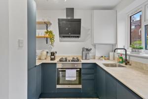 - une cuisine avec des placards bleus et un évier dans l'établissement 2BR Barnet Gem with Front Garden, à Barnet