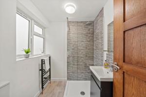 La salle de bains est pourvue d'un lavabo et d'une douche. dans l'établissement 2BR Barnet Gem with Front Garden, à Barnet