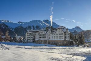 un gran edificio en la nieve frente a las montañas en Cresta Palace Celerina, en Celerina