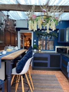 a kitchen with a wooden table with chairs and flowers at 23 Riverside Cottage, Llangollen in Llangollen