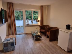 a living room with chairs and a table and a refrigerator at Hotel Osterkrug in Husum