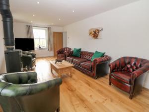a living room with leather furniture and a fireplace at Dove Meadows House in Buxton
