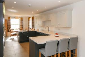 a kitchen with white cabinets and a kitchen island with chairs at Dove Meadows House in Buxton