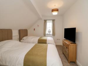a bedroom with two beds and a flat screen tv at Dove Meadows House in Buxton