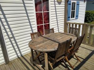 une table et des chaises en bois sur une terrasse dans l'établissement Mobilhome Plouguerneau, à Plouguerneau