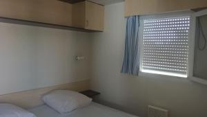 - une petite chambre avec un lit et une fenêtre dans l'établissement Mobilhome Plouguerneau, à Plouguerneau