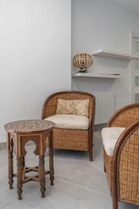 Pokój z wiklinowymi krzesłami, stołem i krzesłem w obiekcie tuGuest Ronda Aparment w Grenadzie