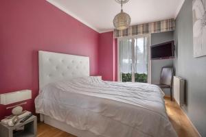 1 dormitorio con cama blanca y pared rosa en Appartement face mer pour 4 personnes, en Pornic