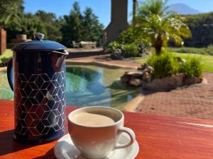 a cup of coffee sitting on a table next to a coffee pot at Rivers Own Guest Lodge in Breerivier