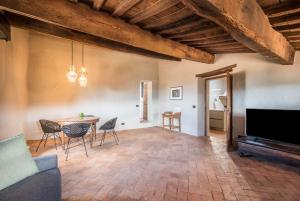 een woonkamer met een tafel en stoelen en een televisie bij La Porticina in Montalcino