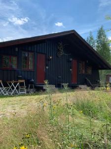 un edificio negro y rojo con mesa y sillas en Hytte nær Ål, 
