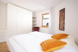 two white beds in a white bedroom with a window at Aurturist Villabassa in Villabassa