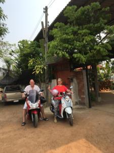 twee mannen op scooters geparkeerd voor een huis bij Baan Mali Lampang Homestay in Lampang