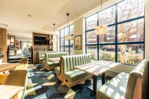 um restaurante com cadeiras e mesas e janelas grandes em Holiday Inn London Sutton, an IHG Hotel em Sutton