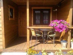a porch with a table and chairs and flowers at Rybacka chata in Rusinowo