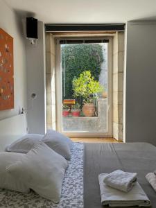 a bedroom with a bed and a window with plants at Le bonheur de la campagne à la ville - Grand studio en plein coeur de la ville in Nîmes