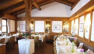 a dining room with tables and chairs with white tablecloths at Landgasthof Osterseen in Iffeldorf