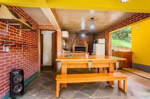 uma cozinha com mesas de madeira e uma parede de tijolos em Sítio Borges em Petrópolis