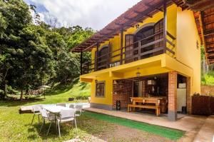 uma casa amarela com uma mesa e cadeiras em Sítio Borges em Petrópolis