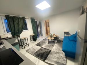 sala de estar con sofá azul y algunas ventanas en La maison bleue, en Athis-Mons