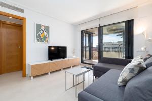 ein Wohnzimmer mit einem Sofa und einem TV in der Unterkunft ApartUP Patacona Sunrise Duplex in Valencia