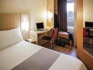 Habitación de hotel con cama y escritorio con ordenador portátil en ibis Toulouse Pont Jumeaux en Toulouse
