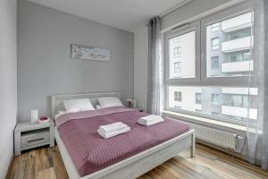 a bedroom with a bed with purple sheets and a window at Bastion View TriApart in Gdańsk