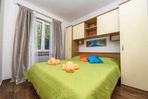 a bedroom with a green bed with orange and blue pillows at Villa Magnolia in Mali Lošinj