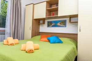 a green bed with orange and blue pillows on it at Villa Magnolia in Mali Lošinj