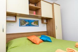 a bedroom with a green bed with orange and blue pillows at Villa Magnolia in Mali Lošinj